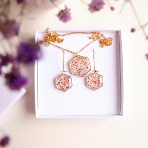 Collier et boucles d'oreilles pendantes avec de fleurs séchées multicolore en résine. Ensemble de bijoux doré en forme de hexagonale. Parure