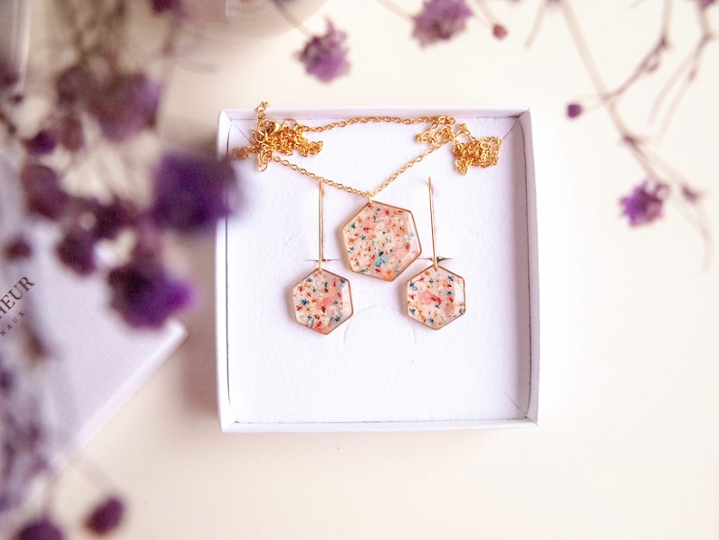 Collier et boucles d'oreilles pendantes avec de fleurs séchées multicolore en résine. Ensemble de bijoux doré en forme de hexagonale. Parure