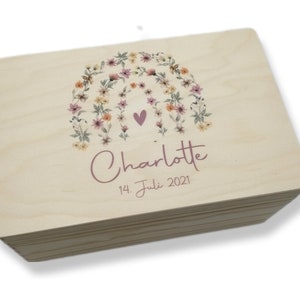 Könnte beinhalten: Eine Holzkiste mit einem Blumendesign und dem Namen "Charlotte" sowie dem Datum "14. Juli 2021" auf dem Deckel.