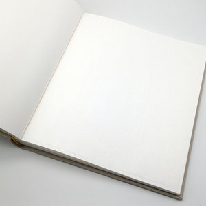 May include: An open blank book with a beige cover and white pages.