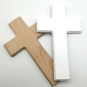 May include: Two wooden crosses, one white and one natural wood, are stacked on top of each other. The white cross is on top of the natural wood cross.
