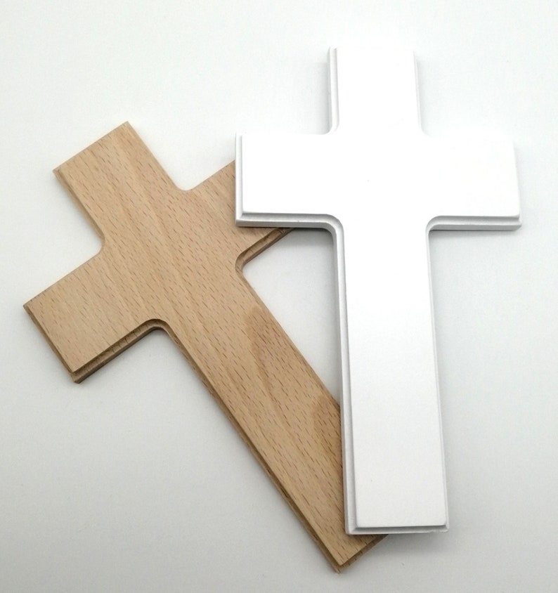 May include: Two wooden crosses, one white and one natural wood, are stacked on top of each other. The white cross is on top of the natural wood cross.