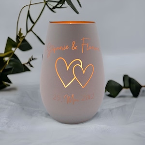 May include: White ceramic candle holder with two hearts cut out and the text "Stephanie & Florian 25. May 2012".