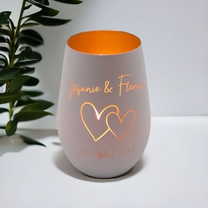 May include: White candle holder with two hearts cut out and the text "Stefanie & Florian 25. May 2012" engraved on the side. The candle holder has a gold interior.