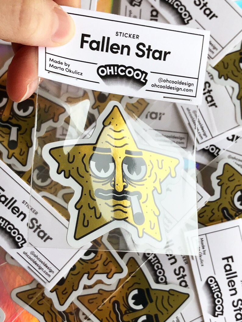 Op de afbeelding: Een gouden sticker met een cartoonster met een smeltend gezicht, een zonnebril en een sigaret. De sticker is gelabeld met "Fallen Star" en "OH!COOL" met het websiteadres "ohcooldesign.com".
