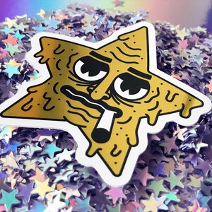 Op de afbeelding: Een gouden sticker in de vorm van een ster met een cartoon gezicht, druipend met een kleverige substantie. Het gezicht heeft een hangende uitdrukking, met &eacute;&eacute;n oog gesloten en het andere wijd open. De ster houdt een sigaret in zijn mond.