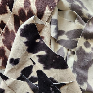 May include: Close-up of fabric swatches in various animal print patterns. The swatches are in shades of brown, black, white, and gray. The fabric has a soft, fuzzy texture.