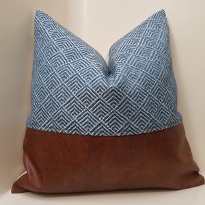 May include: A blue and white geometric patterned pillow with a brown faux leather bottom.