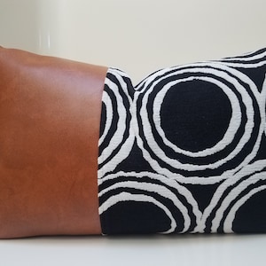 May include: A brown leather and black and white patterned pillow with a geometric design.