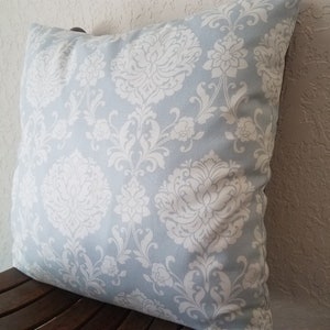 May include: A light blue throw pillow with a white damask pattern.