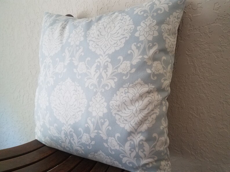 May include: A light blue throw pillow with a white damask pattern.