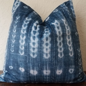 May include: A blue and white patterned throw pillow with a geometric design. The pillow is made of a soft, textured fabric.