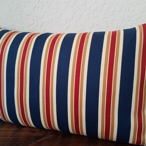 May include: A navy blue, red, and gold striped throw pillow. The pillow is rectangular and has a soft, plush feel.