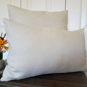 May include: Two beige linen pillow covers, one on top of the other. The pillow covers are made of a soft, natural fabric and have a simple, elegant design.