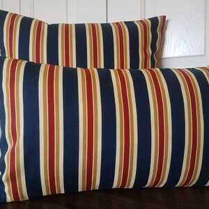 May include: Two striped throw pillows with a navy blue, red, and beige pattern.