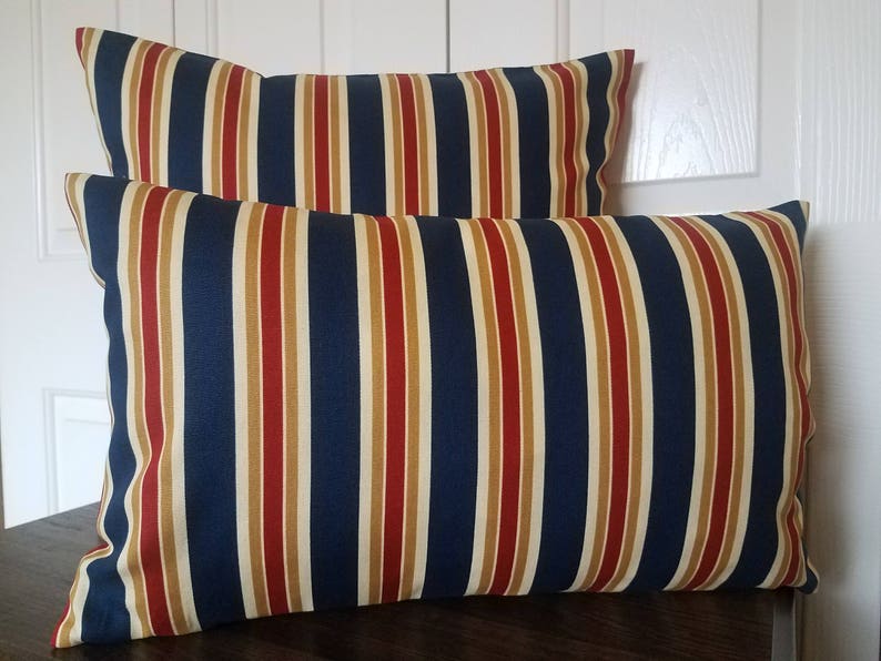 May include: Two striped throw pillows with a navy blue, red, and beige pattern.