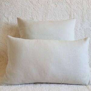 May include: Two off-white linen pillow covers. The pillow covers are rectangular and have a subtle texture.
