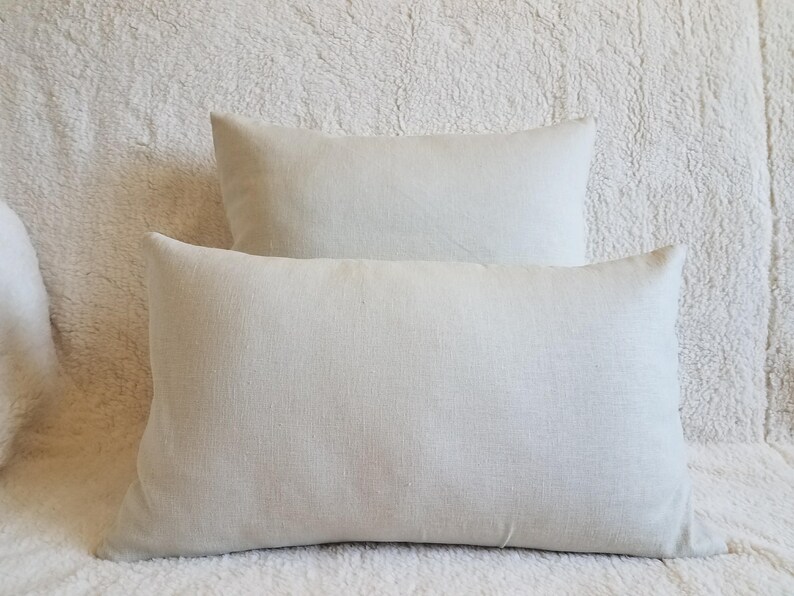 May include: Two off-white linen pillow covers. The pillow covers are rectangular and have a subtle texture.
