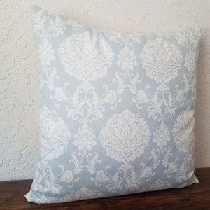 May include: A light blue throw pillow with a white damask pattern.