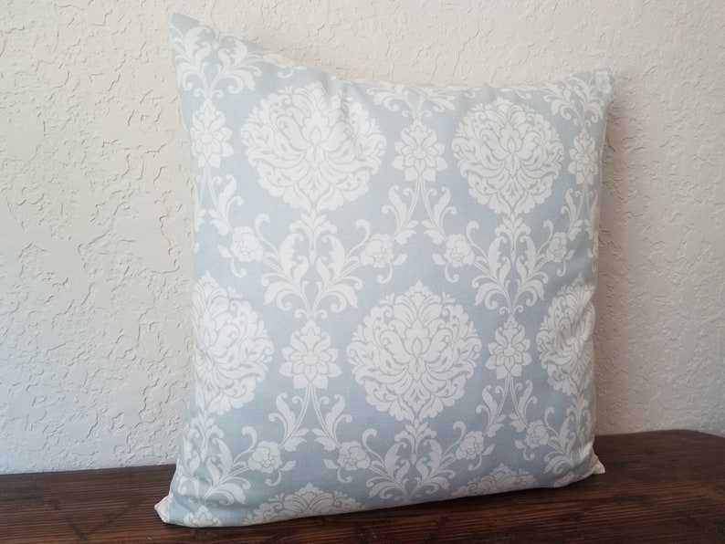 May include: A light blue throw pillow with a white damask pattern.