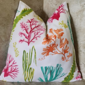 May include: White pillow with a colorful coral reef pattern. The pillow features pink, orange, green, and blue coral designs.