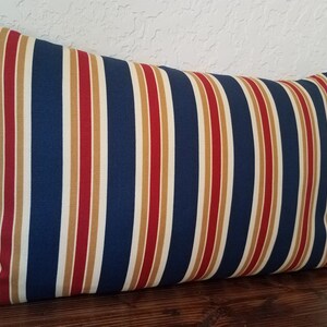 May include: A blue, red, and cream striped pillow cover. The pillow is rectangular and has a soft, textured fabric.