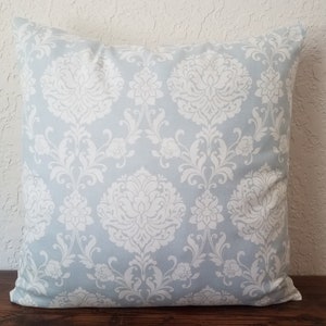 May include: A light blue throw pillow with a white damask pattern.