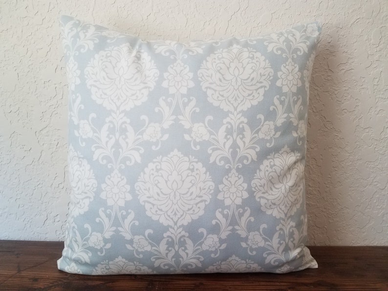 May include: A light blue throw pillow with a white damask pattern.