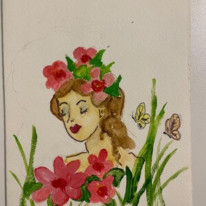 May include: Watercolor painting of a woman with brown hair and a floral crown, surrounded by pink flowers and green grass. Two butterflies flutter nearby. The woman has closed eyes and red lips.