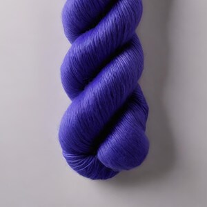 May include: A skein of vibrant purple yarn, tightly twisted and displayed against a neutral background. The yarn appears soft and has a slight sheen, suggesting a luxurious fiber. Ideal for knitting or crochet projects.