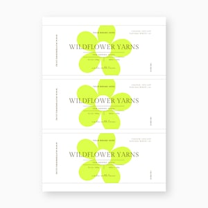 Op de afbeelding: Drie witte labels met de tekst "WILDFOWER YARNS" in een bloemmotief. De labels bevatten ook de tekst "100% Merino Wool" en "100g". De labels zijn bedrukt met een lichtgroene kleur en de tekst "made with love."