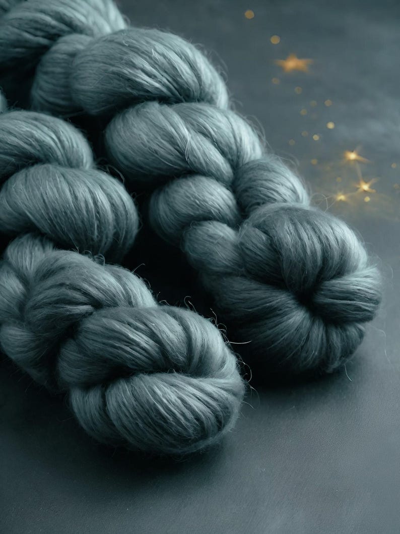 May include: Close-up of a skein of teal-colored yarn. The yarn is thick and fluffy, with a soft, textured appearance. The image is well-lit, highlighting the yarn's color and texture. The yarn is likely used for knitting or crocheting.