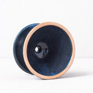 May include: A dark blue ceramic planter with a light brown rim. The planter has a drainage hole in the bottom.