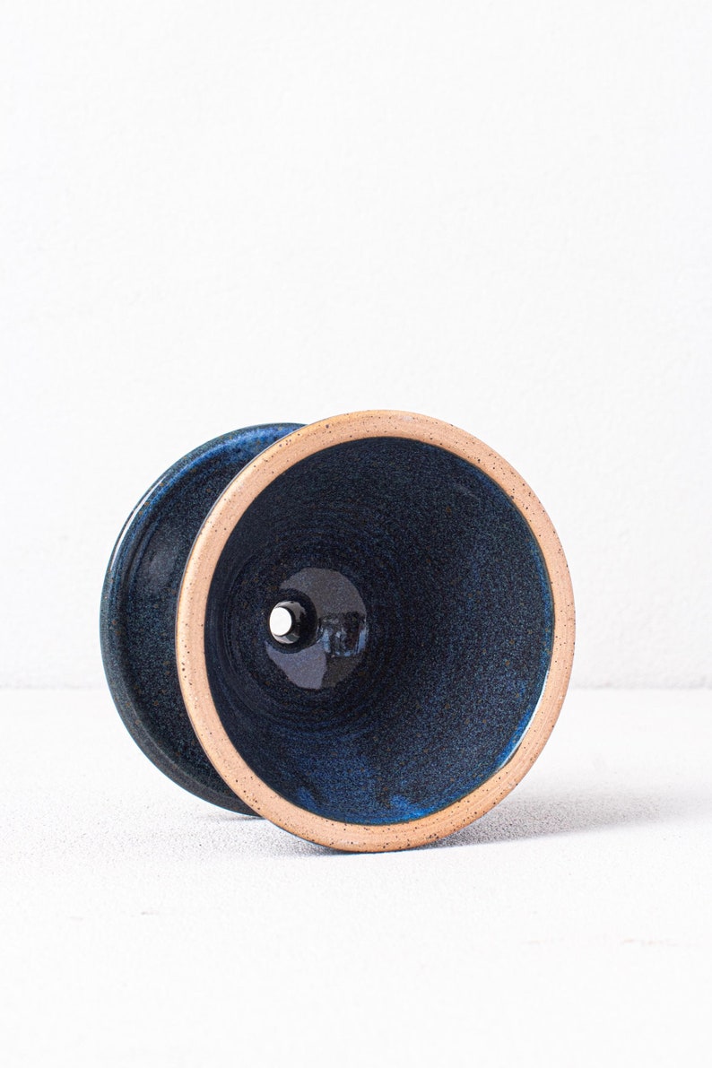 May include: A dark blue ceramic planter with a light brown rim. The planter has a drainage hole in the bottom.