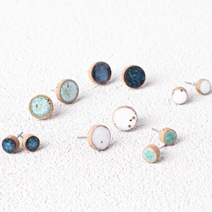 May include: Assortment of ceramic stud earrings in various shades of blue and white. The earrings are round and have a simple design.
