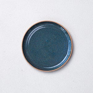 May include: A blue ceramic plate with a speckled glaze and a brown rim.