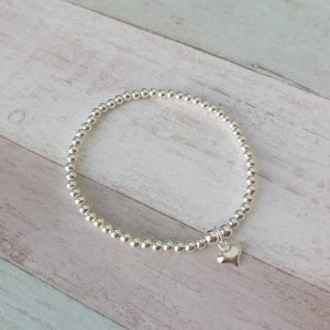 May include: A silver beaded bracelet with a small silver heart charm.