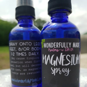 May include: Two blue glass spray bottles with black labels. The label on the left bottle says "SPRAY ONTO LEGS FEET, &/OR BODY 1-2 TIMES DAILY. May cause tingling sensation when first used, but will decrease with use, as magnesium levels are restored. wwwWonderfullyMadeLo". The label on the right bottle says "WONDERFULLY MADE Psalms 139:14 MAGNESIUM spray".