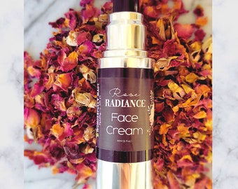 May include: A silver pump bottle with a black cap filled with a rose-colored face cream. The label reads "Rose Radiance Face Cream" and "Wonderfully Made" with a small leaf icon. The bottle is surrounded by dried rose petals.