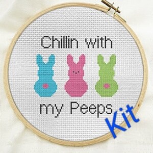 Peut inclure: Kit de point de croix avec trois personnages de marshmallow en forme de lapin de couleur, avec le texte "Chillin' with my peeps".