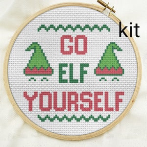 Puede incluir: Un kit de punto de cruz con un fondo blanco y bordado verde y rojo. El dise&ntilde;o dice "Go Elf Yourself" con dos gorros de elfo a cada lado del texto.