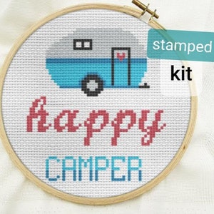 Puede incluir: Un kit de punto de cruz estampado con una caravana azul y el texto "Happy Camper".