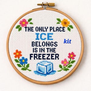 Op de afbeelding: Een borduurring met kruissteek met de tekst "THE ONLY PLACE ICE BELONGS IS IN THE FREEZER". Het ontwerp bevat een blauwe ijsblokjes en kleurrijke bloemen. Het woord "kit" is ook opgenomen.