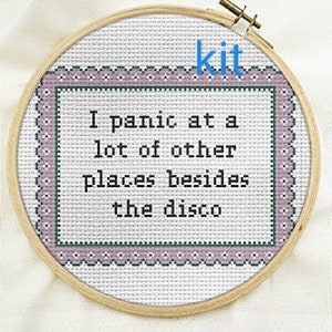 May include: Cross stitch kit featuring the text "I panic at a lot of other places besides the disco". The kit is displayed in a white embroidery hoop with a pink and green border.