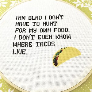 May include: White embroidery hoop with a black embroidered saying: "I am glad I don't have to hunt for my own food. I don't even know where tacos live."  A yellow embroidered taco is in the bottom right corner.