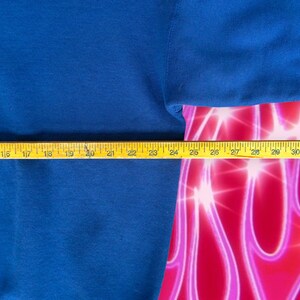 May include: A close-up of a blue sweatshirt with a yellow measuring tape across the bottom. The tape measures 14 to 32 inches.