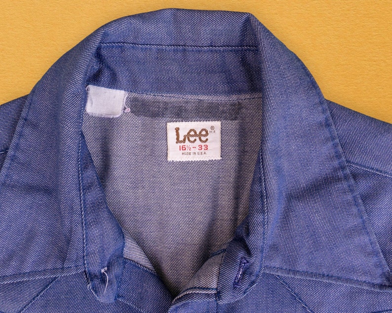 May include: A blue denim shirt with a button-down collar and a Lee label that reads "16 1/2 - 33" and "Made in U.S.A."