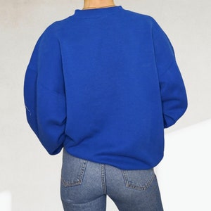 May include: A royal blue sweatshirt with long sleeves and a crew neck.