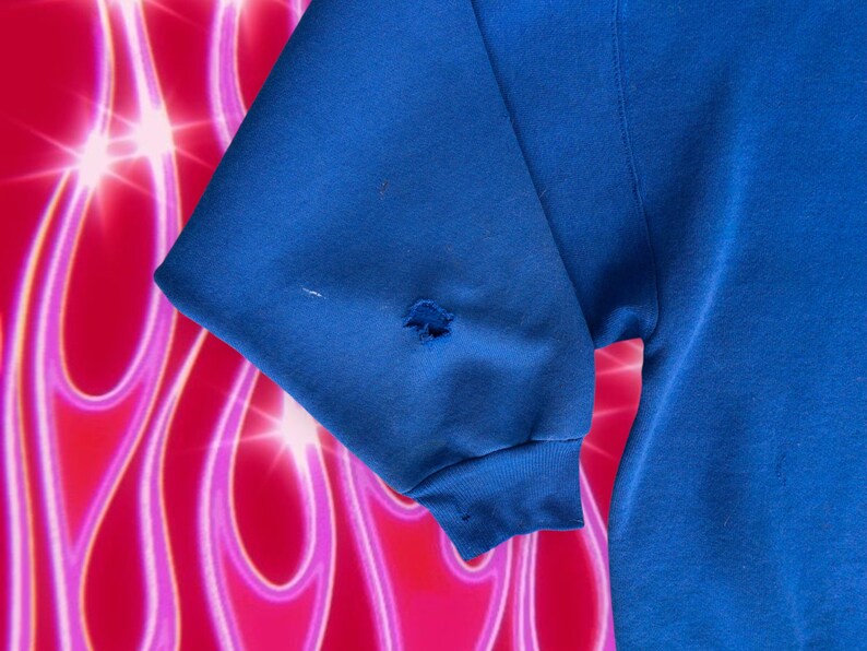 May include: A blue sweatshirt with a small hole in the sleeve.