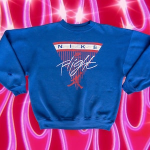 May include: A blue sweatshirt with a red, white, and blue Nike Flight logo. The logo features a basketball player in silhouette and the word "Flight" in a stylized font.